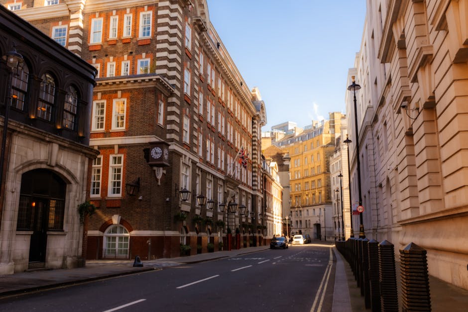 A wet city street scene featuring multi-storey red-brick residential buildings with white window frames and bay windows, typical of Westminster architecture in London. In the foreground, the pavement